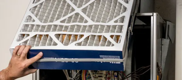 Technician sliding a new pleated air filter into a furnace