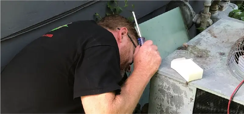 Greenway technician servicing an outdoor HVAC unit